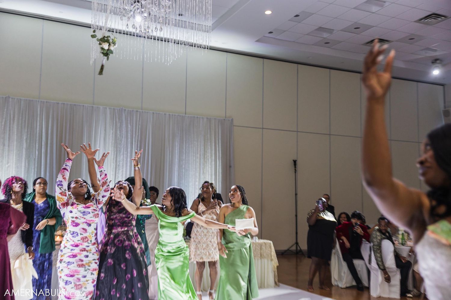 Wedding guests dancing with raised arms during a lively reception celebration.