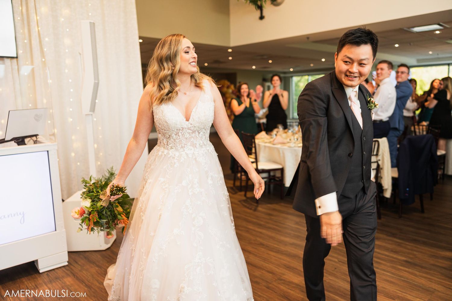 Newlyweds dance together on wooden floor during wedding reception celebration.