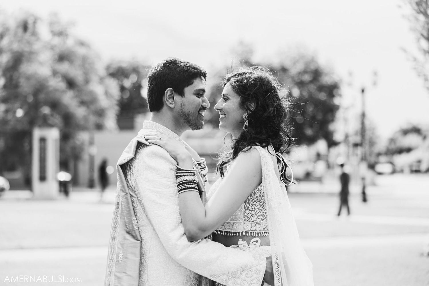 An intimate black and white portrait of a couple embracing outdoors.