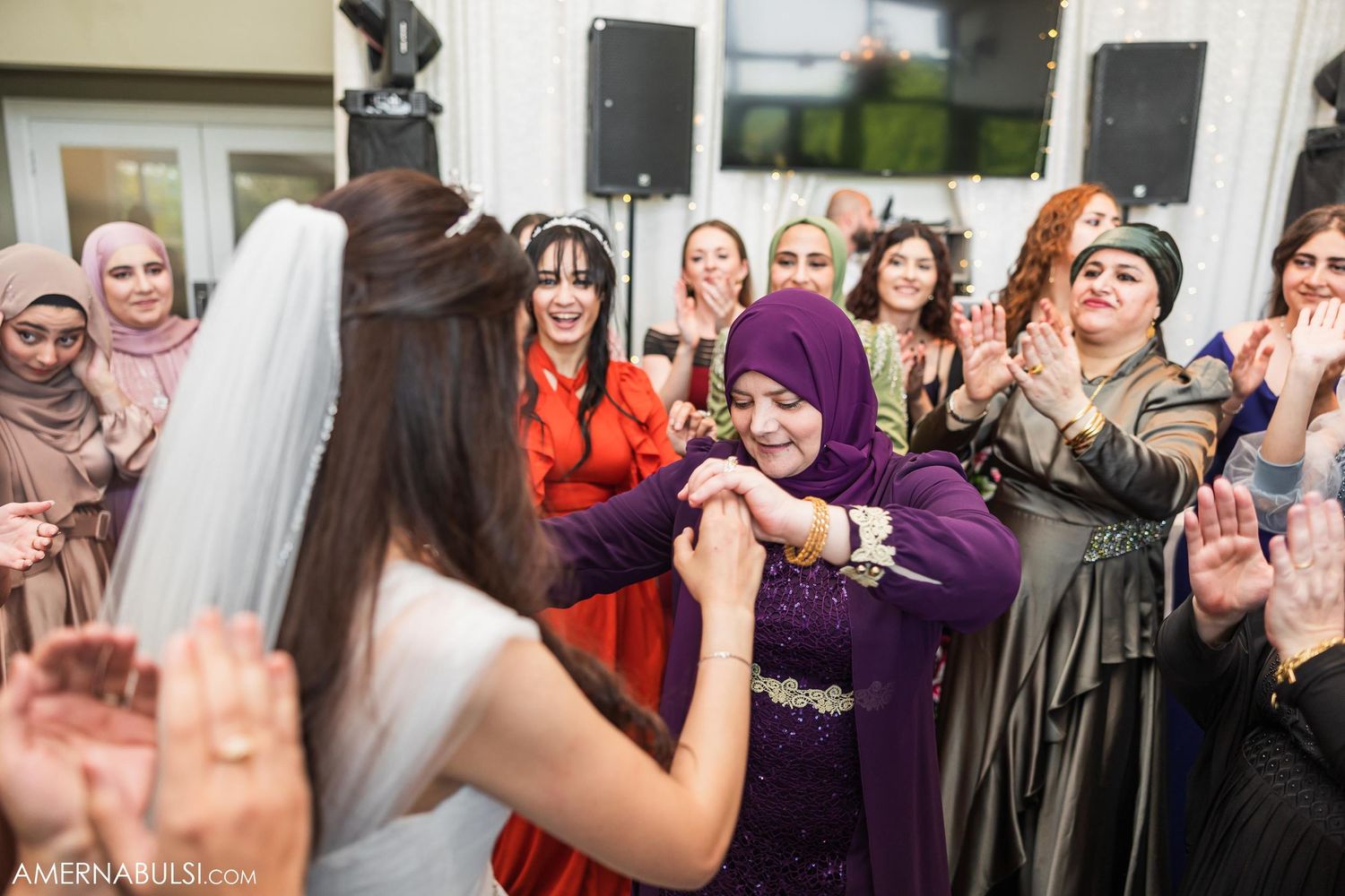 Wedding celebration showing guests dancing together in traditional cultural attire at an indoor reception.