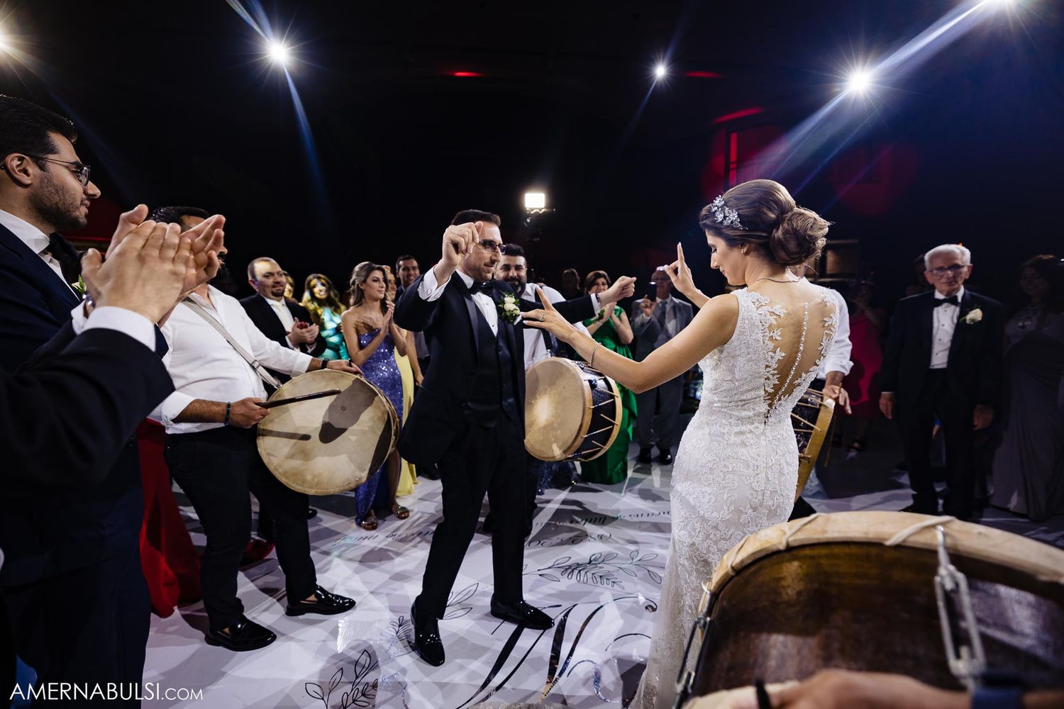 A couple dances surrounded by musicians with drums at a wedding celebration.
