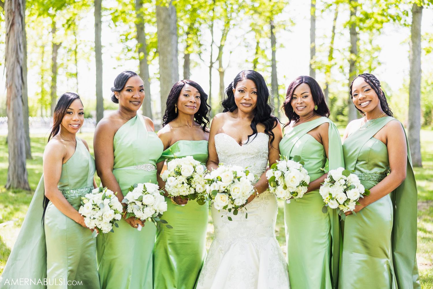 Happy bridesmaids in mint green dresses share candid moment with bride while holding white bouquets.