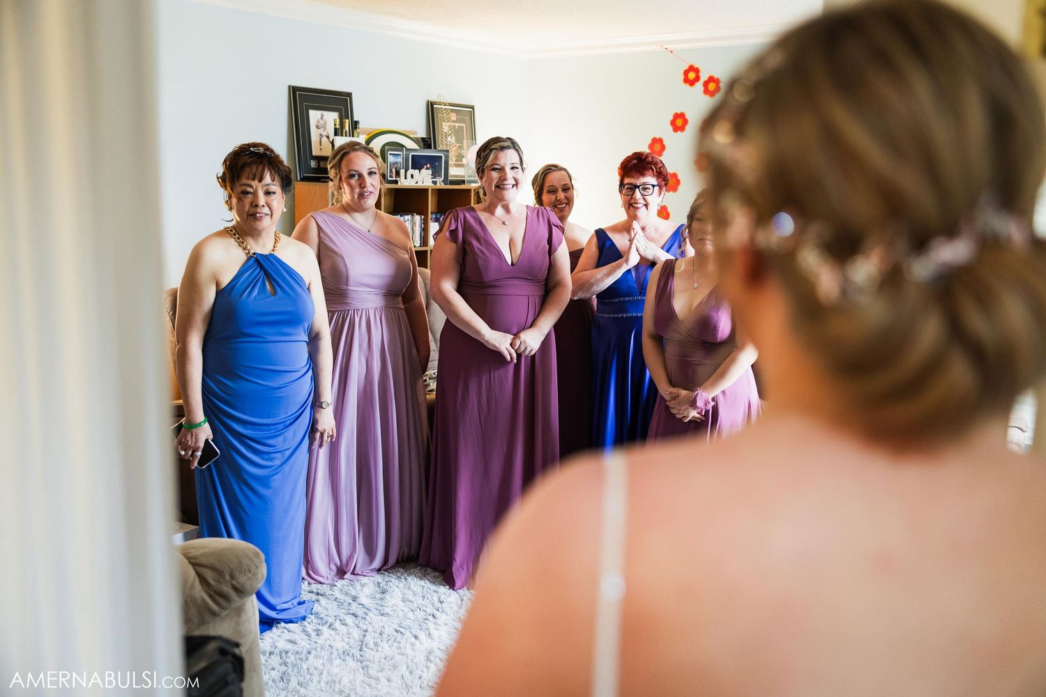 Bridesmaids in colorful dresses gather excitedly to see the bride on her wedding day.