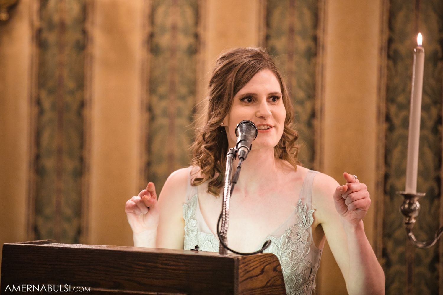 Guests gather at a formal event with ornate wallpaper and candlelit ambiance.