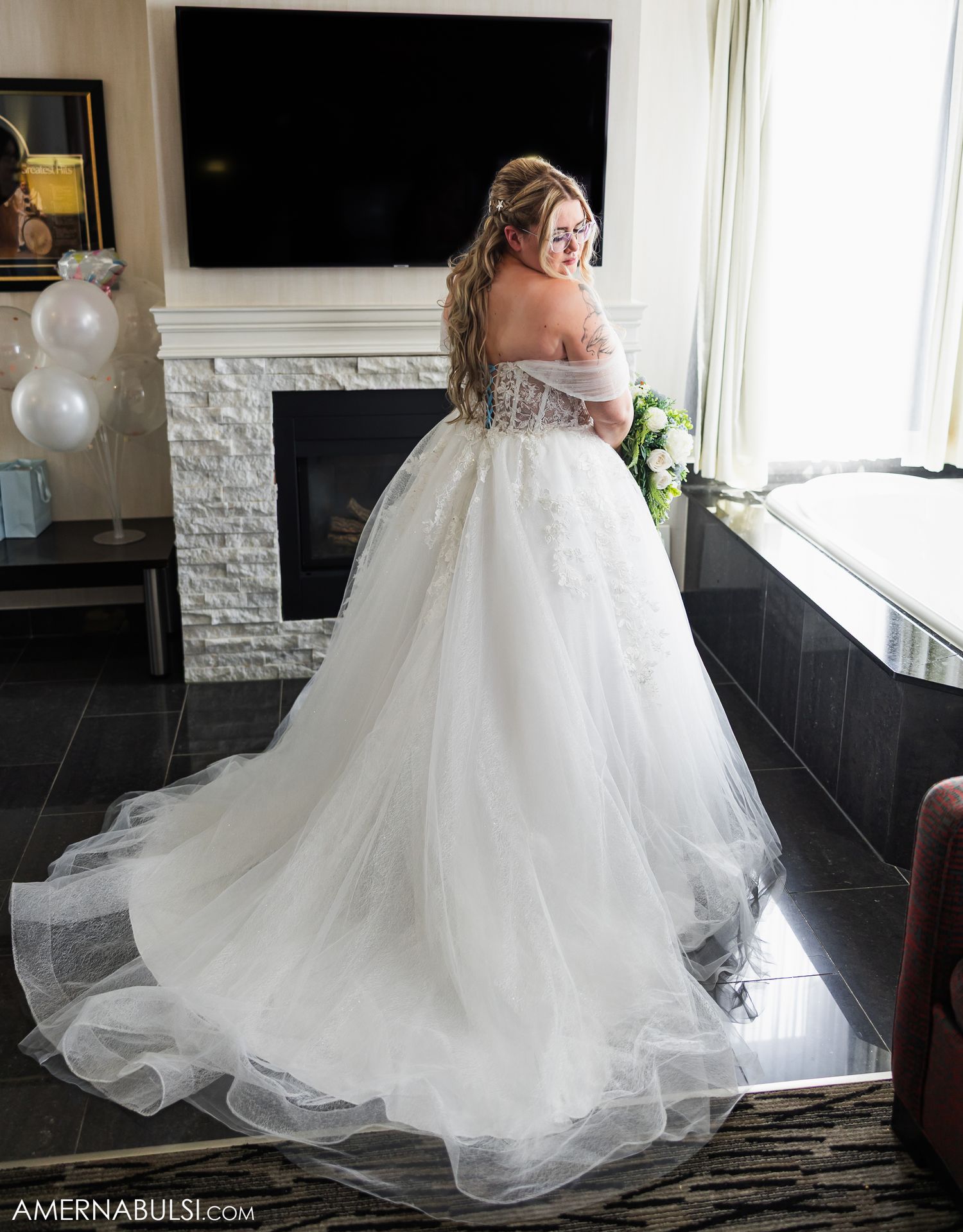 Flowing white wedding gown with delicate tulle skirt photographed in natural window light.