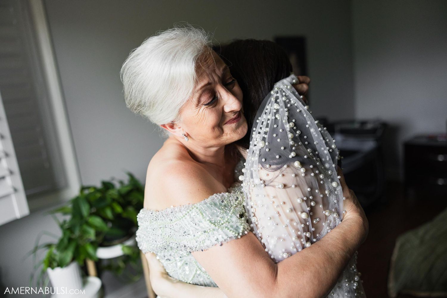 Emotional candid moment with delicate lace veil being held up in natural window light.