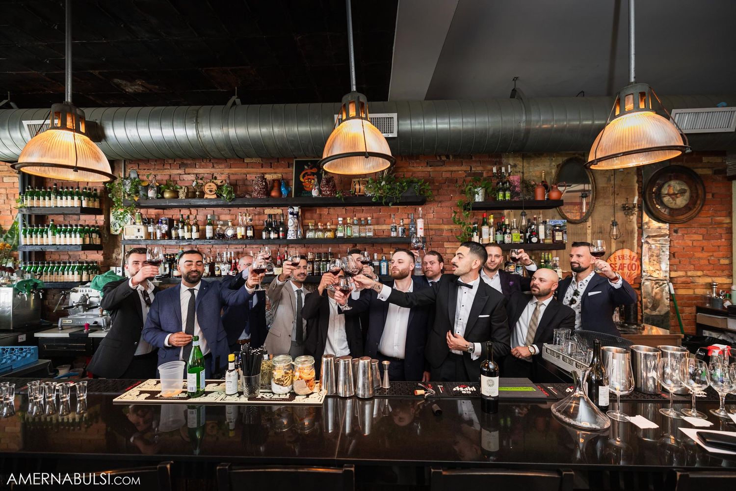 Group gathered at an upscale bar with pendant lighting and exposed brick walls.