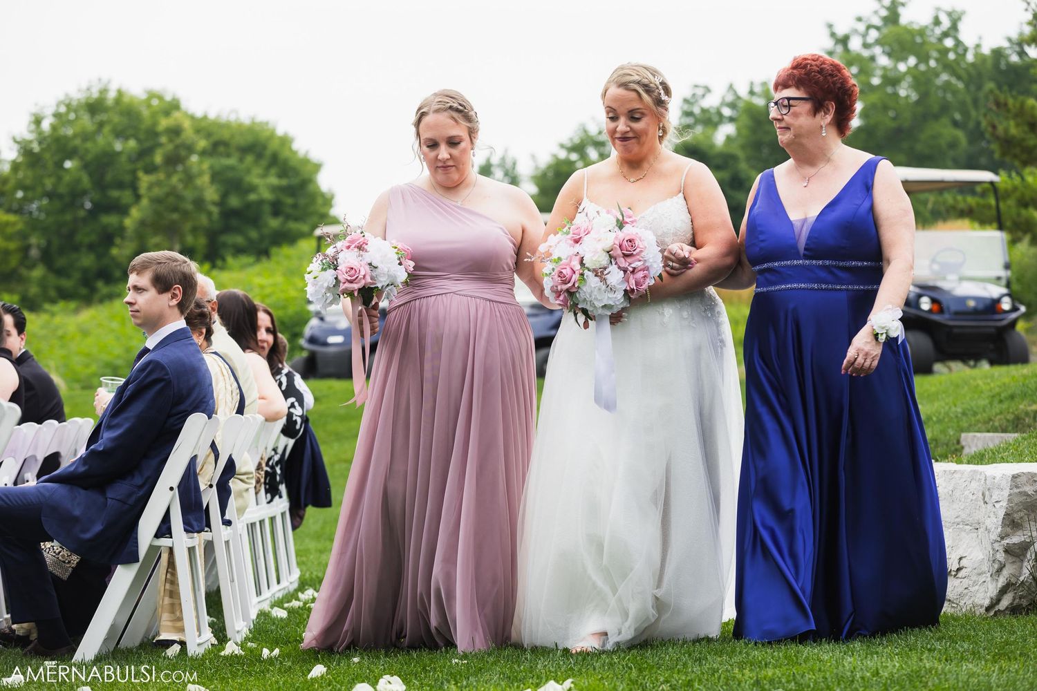 Wedding party members walk together outdoors wearing coordinated mauve and royal blue formal attire.