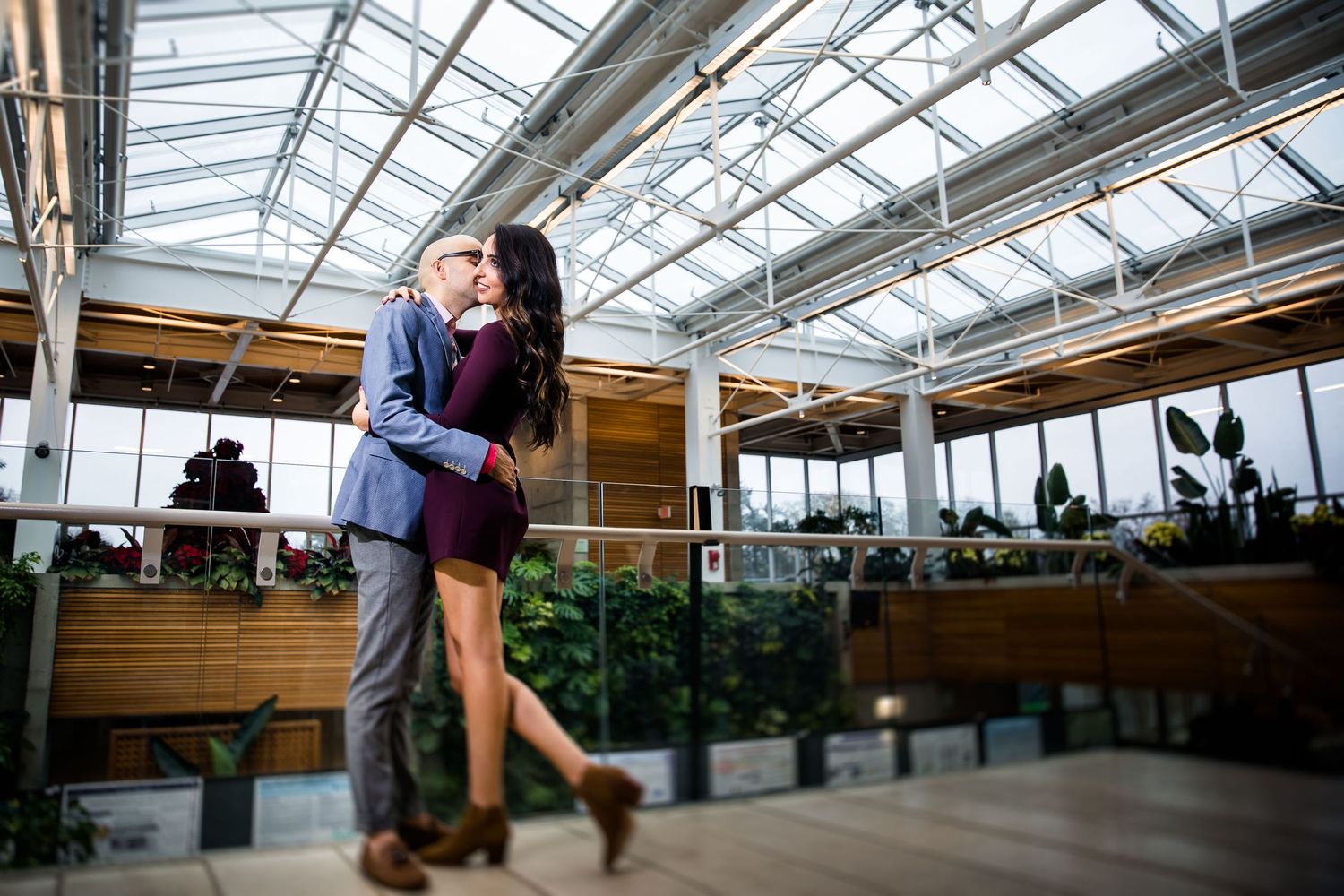 Modern greenhouse interior with glass ceiling and wooden beams creating geometric patterns.