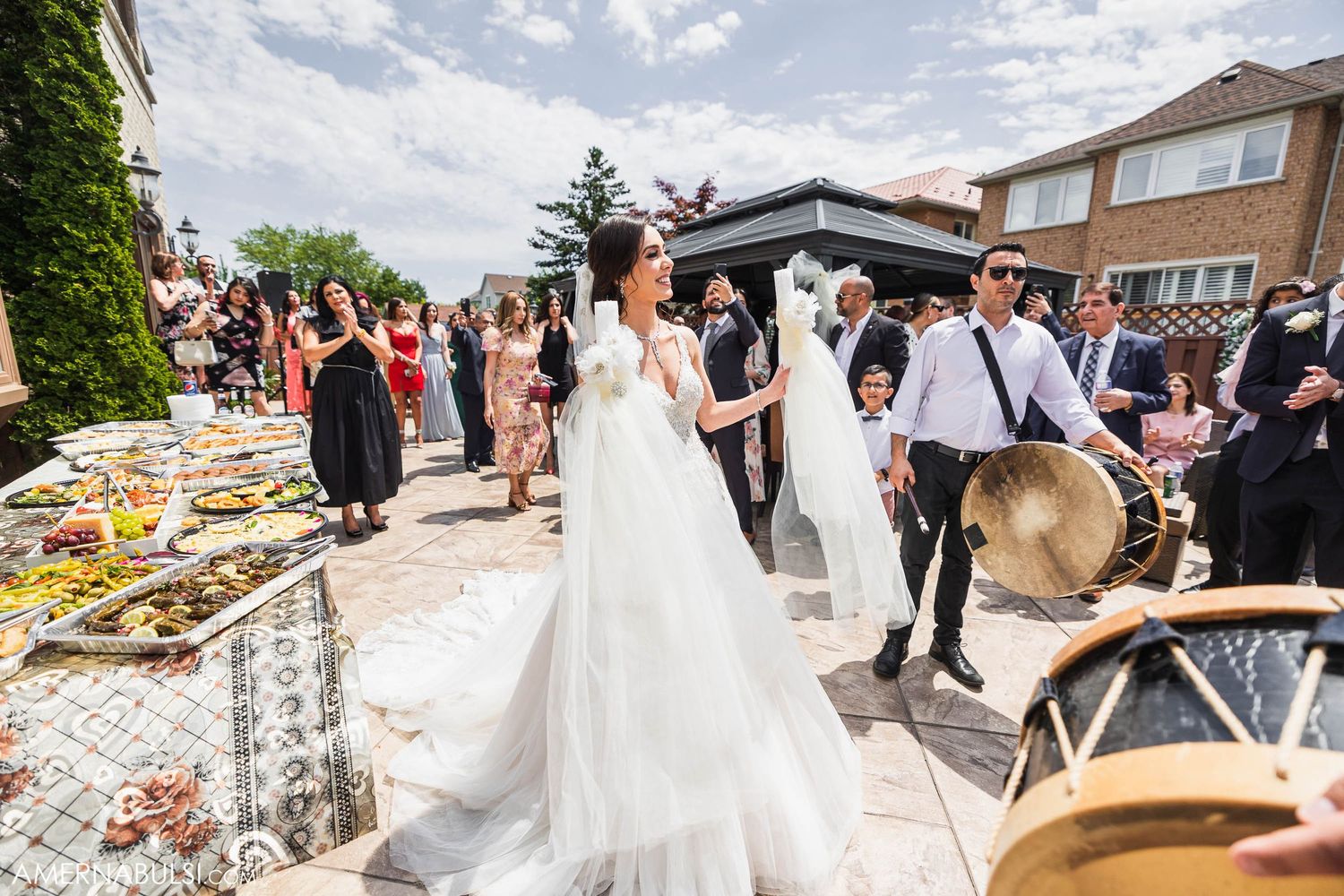 Outdoor wedding reception with buffet tables and guests celebrating on a sunny summer day.