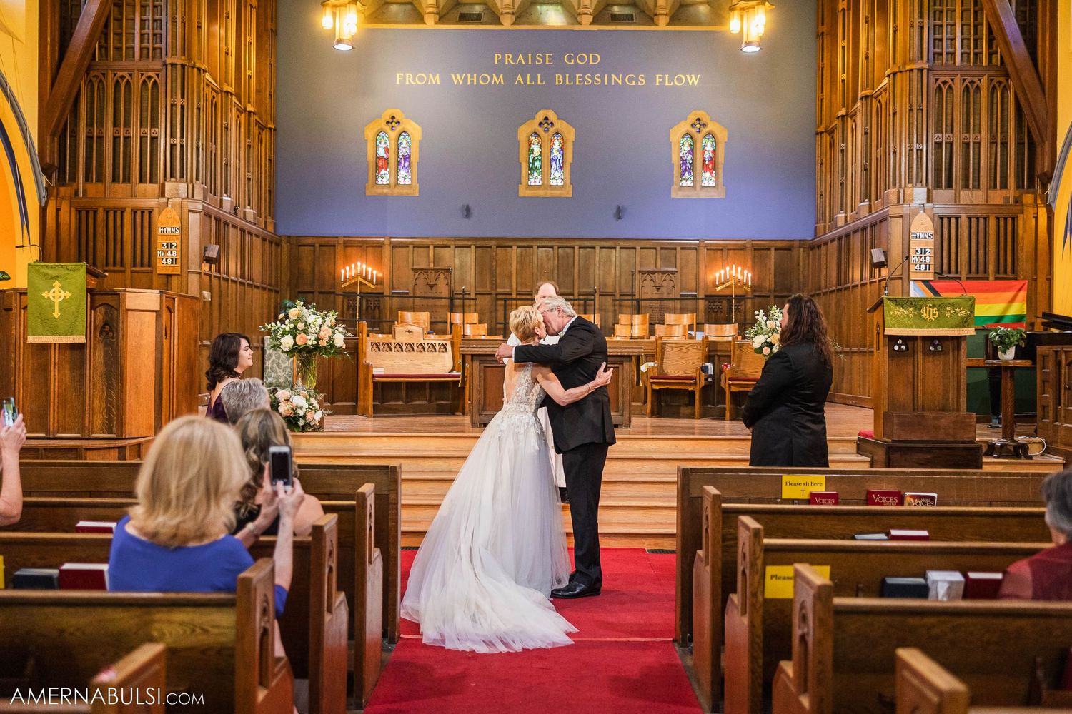 Newlyweds sharing first dance on red carpet in church sanctuary.