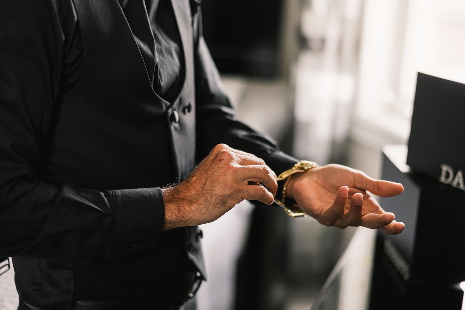 Close-up of hands adjusting cufflinks on a formal black suit.