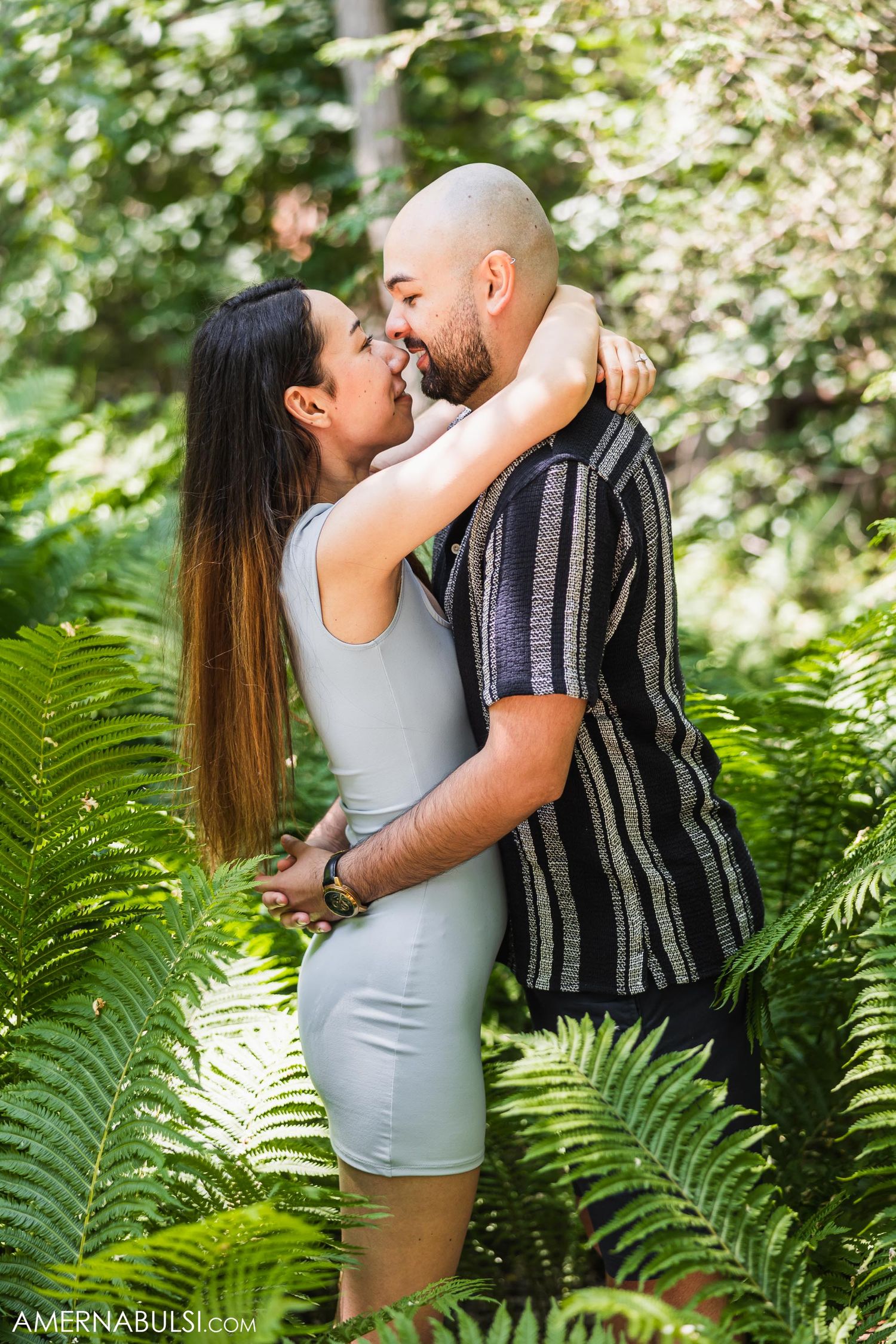A romantic moment shared between a couple surrounded by lush ferns.