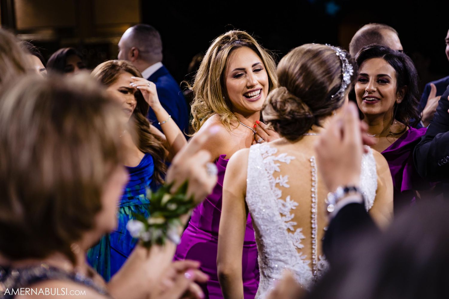 Wedding guests dancing and celebrating in a crowded reception venue.