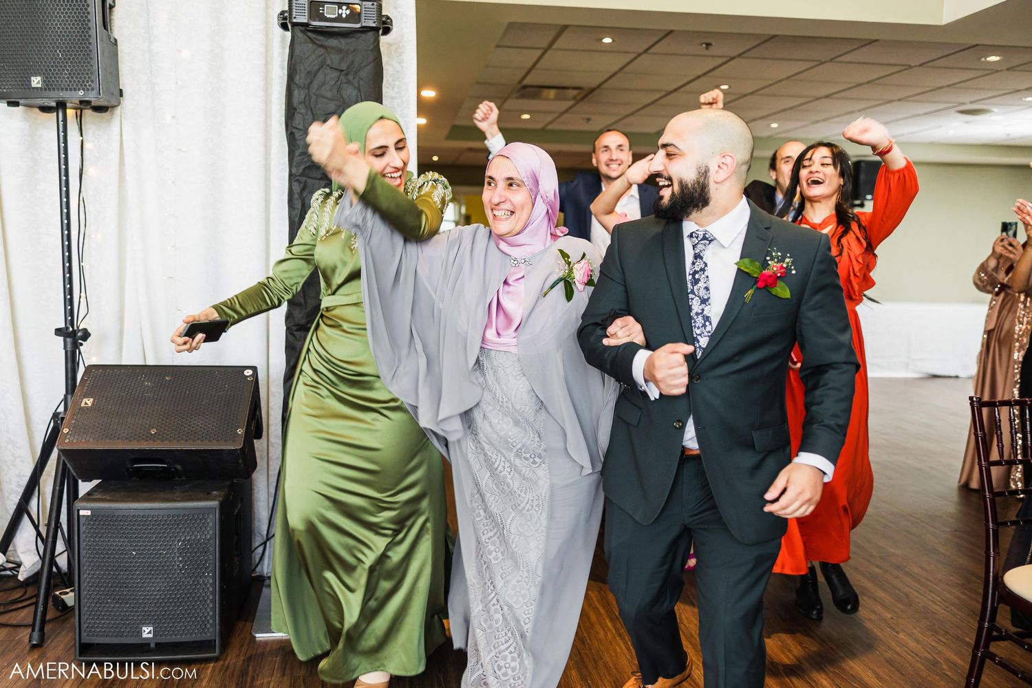Wedding guests dancing and celebrating energetically on the dance floor.
