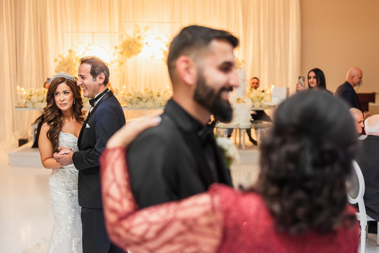 Wedding celebration in an elegant ballroom with romantic ambient lighting and decorative backdrop.