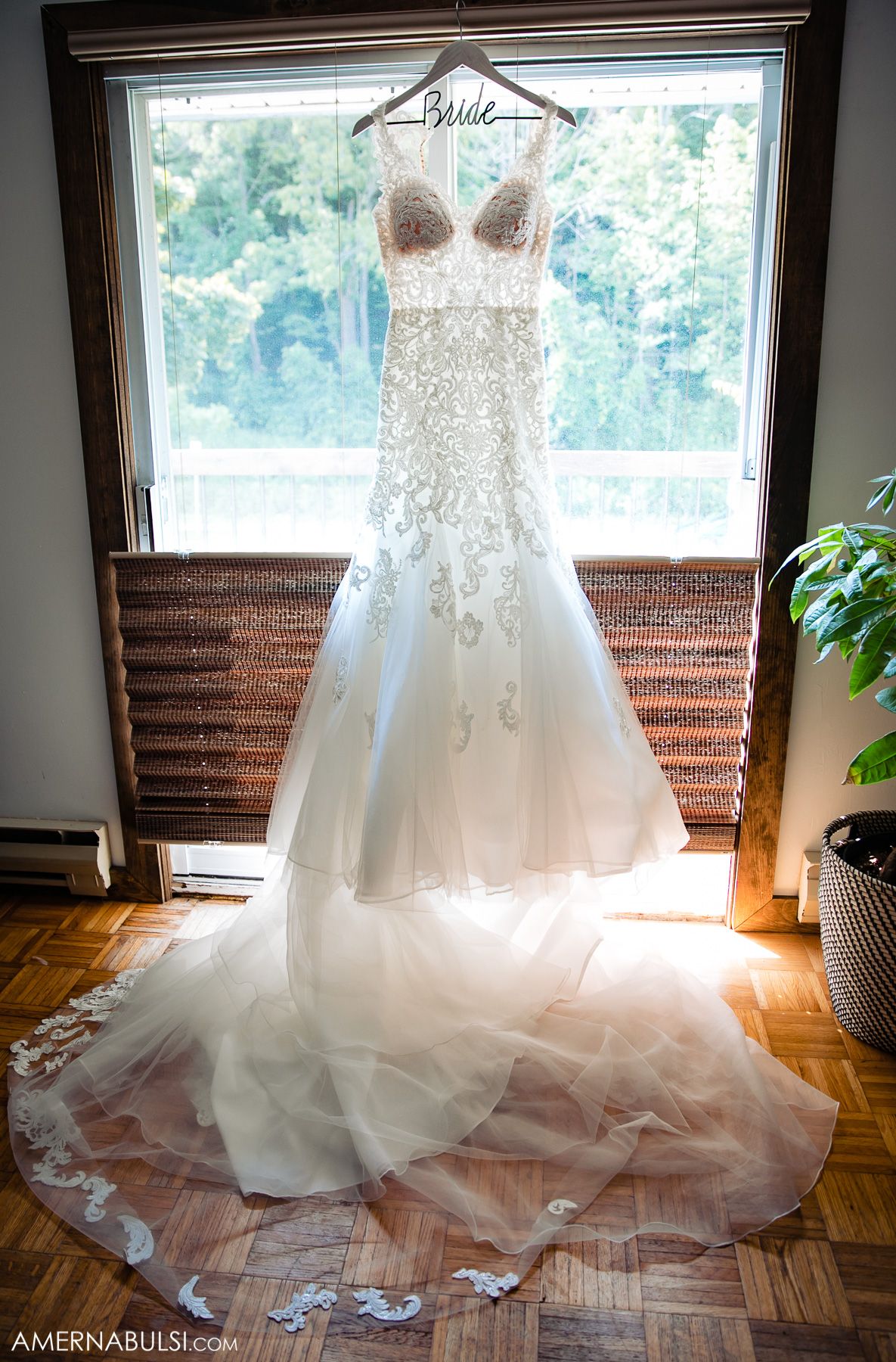 A white lace wedding gown with sweetheart neckline displayed on a hanger near a sunlit window in progressive shots.