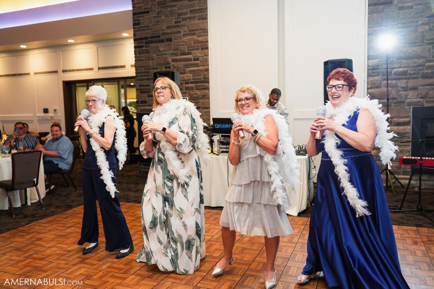 Group of wedding guests performs choreographed dance routine with feather boas.
