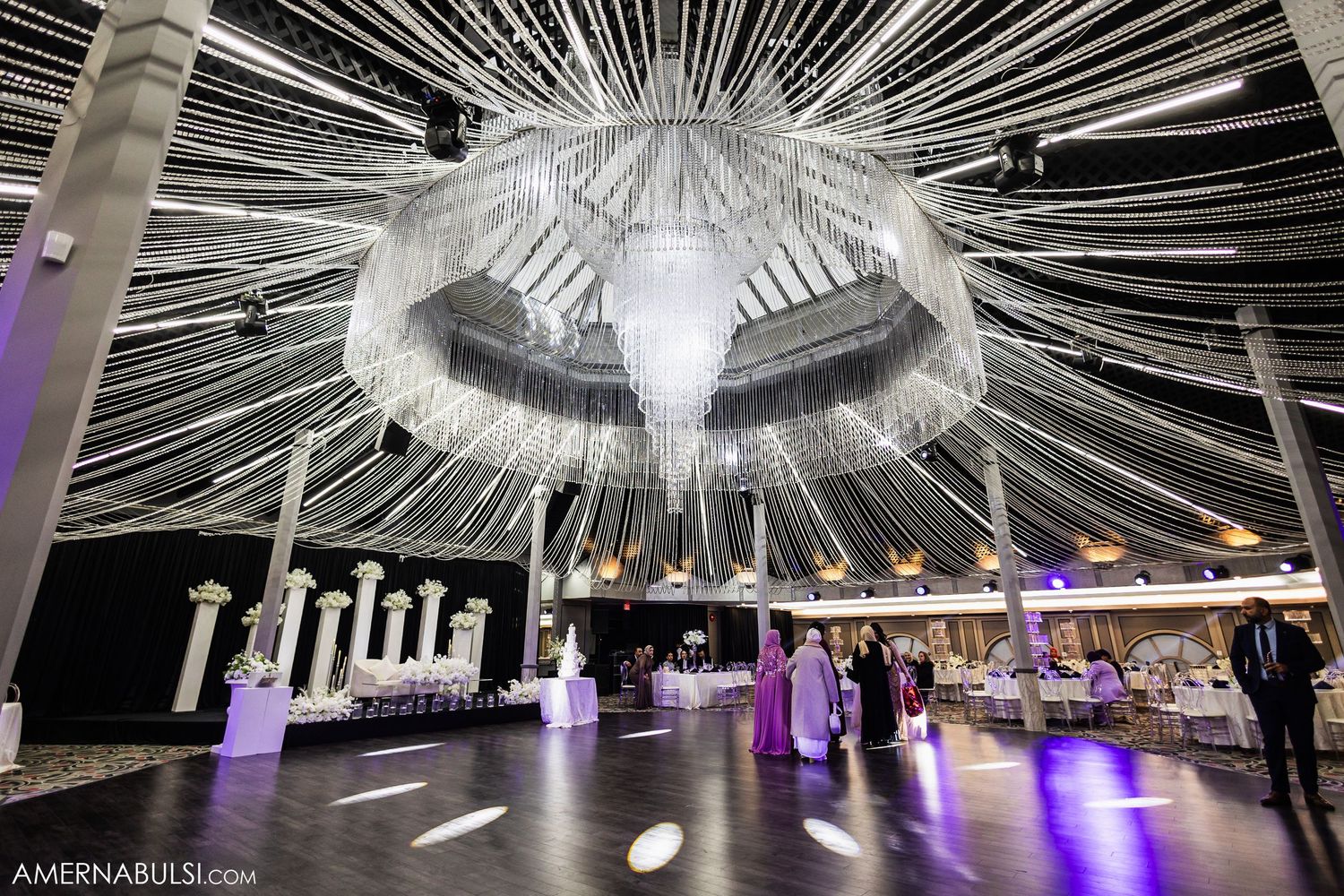 Elegant wedding reception venue with dramatic white string light canopy and purple accent lighting creating a magical atmosphere.