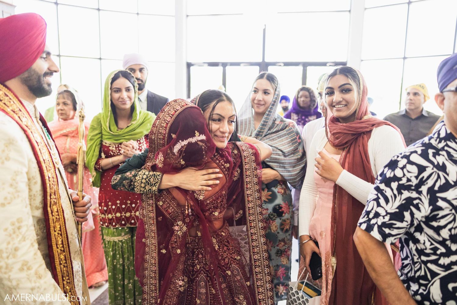 Wedding guests in colorful traditional attire celebrating during Sikh ceremony.