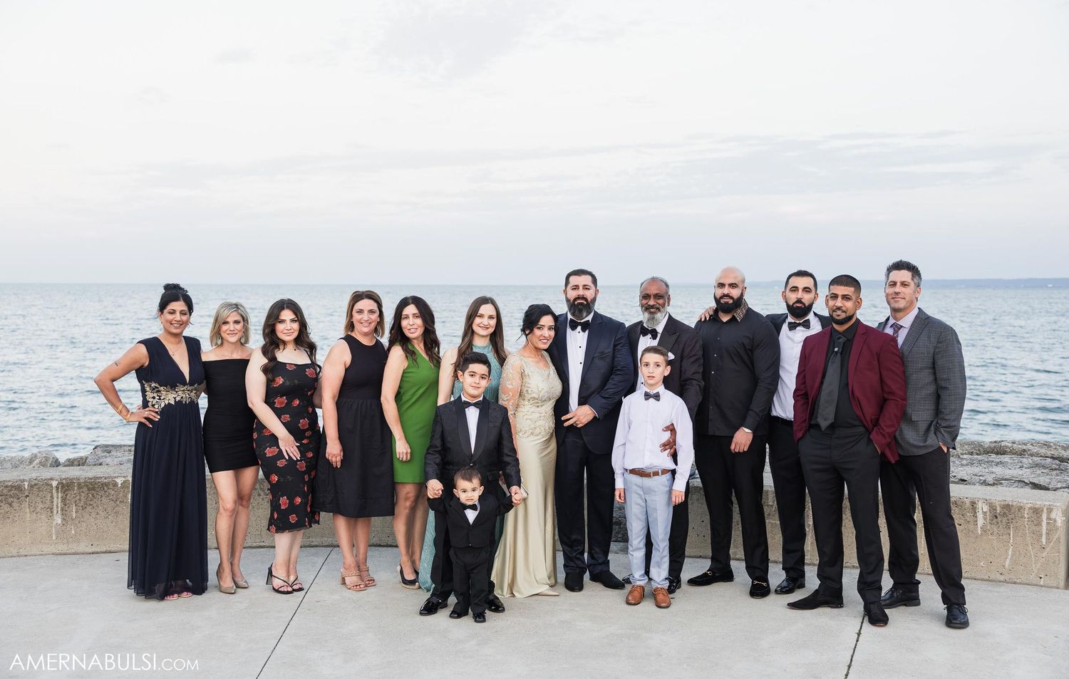 Formal group photo of wedding party members posed by the waterfront.