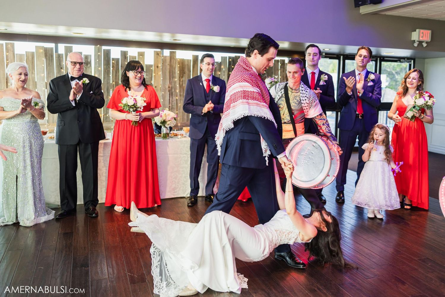 Wedding party performs a fun dance with drums during reception celebration on dance floor.