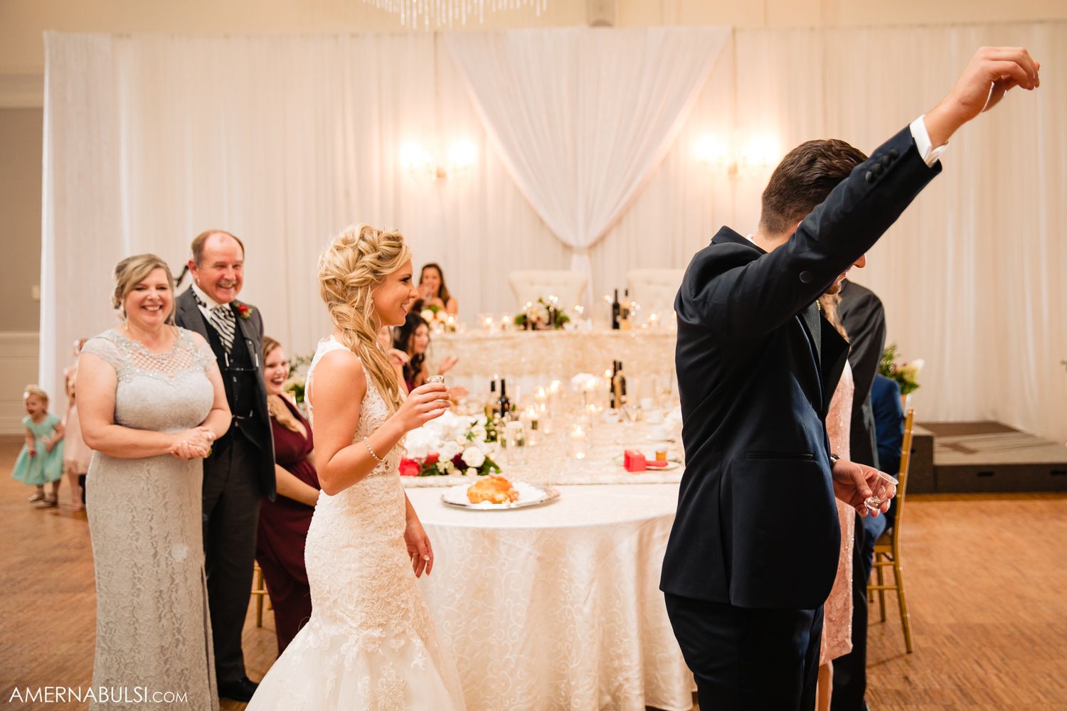 Wedding guests dance and celebrate together during a reception in an elegant white ballroom.