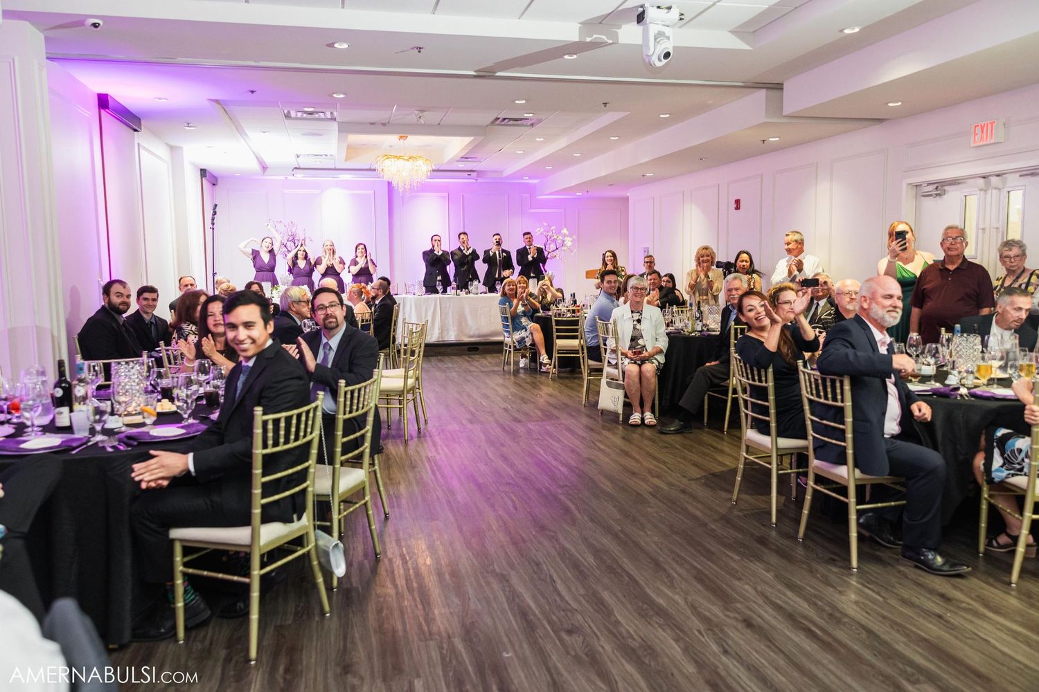 Wedding reception venue with purple uplighting and elegant table settings in a spacious banquet room.