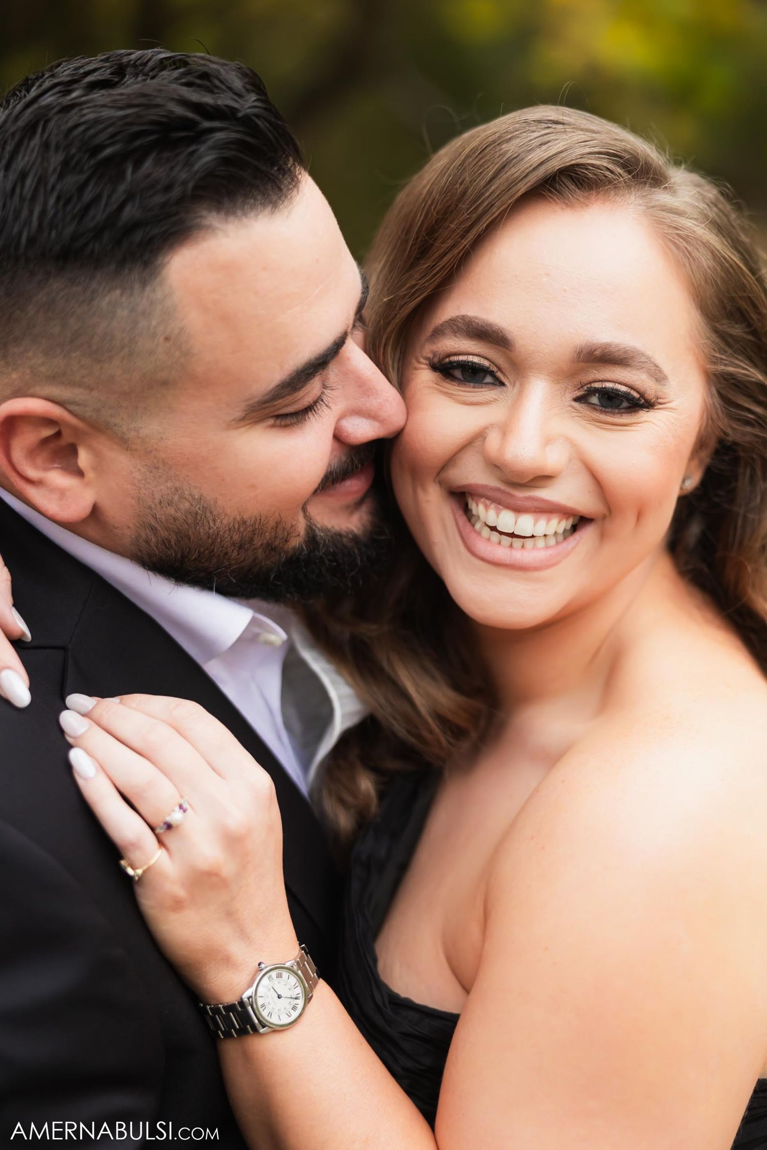Intimate close-up of couple laughing and embracing in formal attire outdoors.