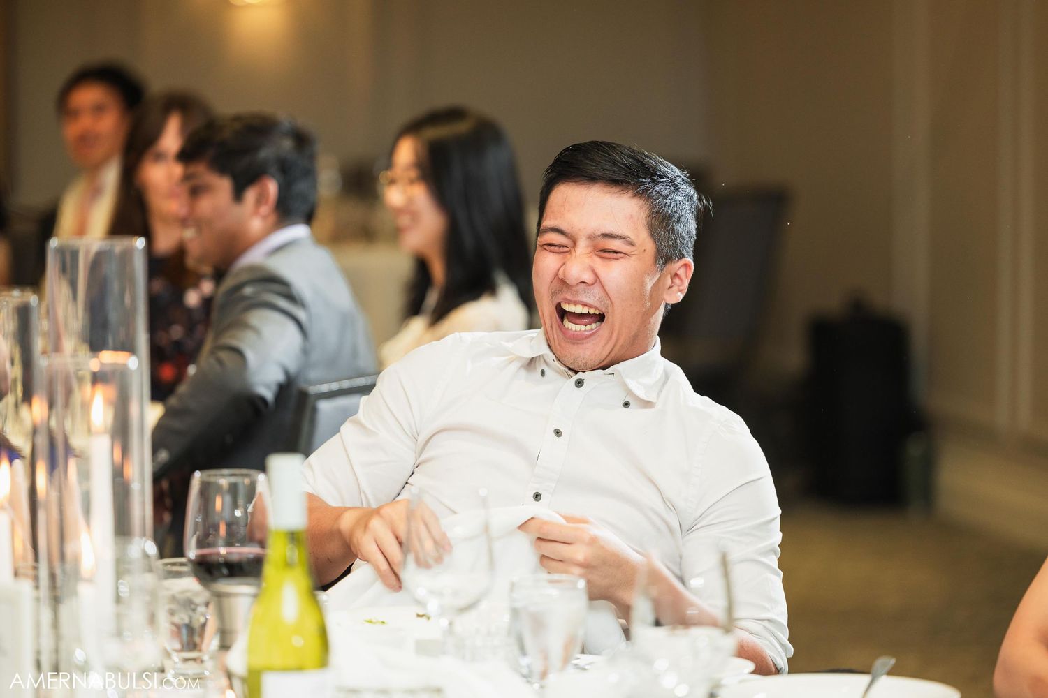 Guest laughing heartily during a wedding reception dinner.
