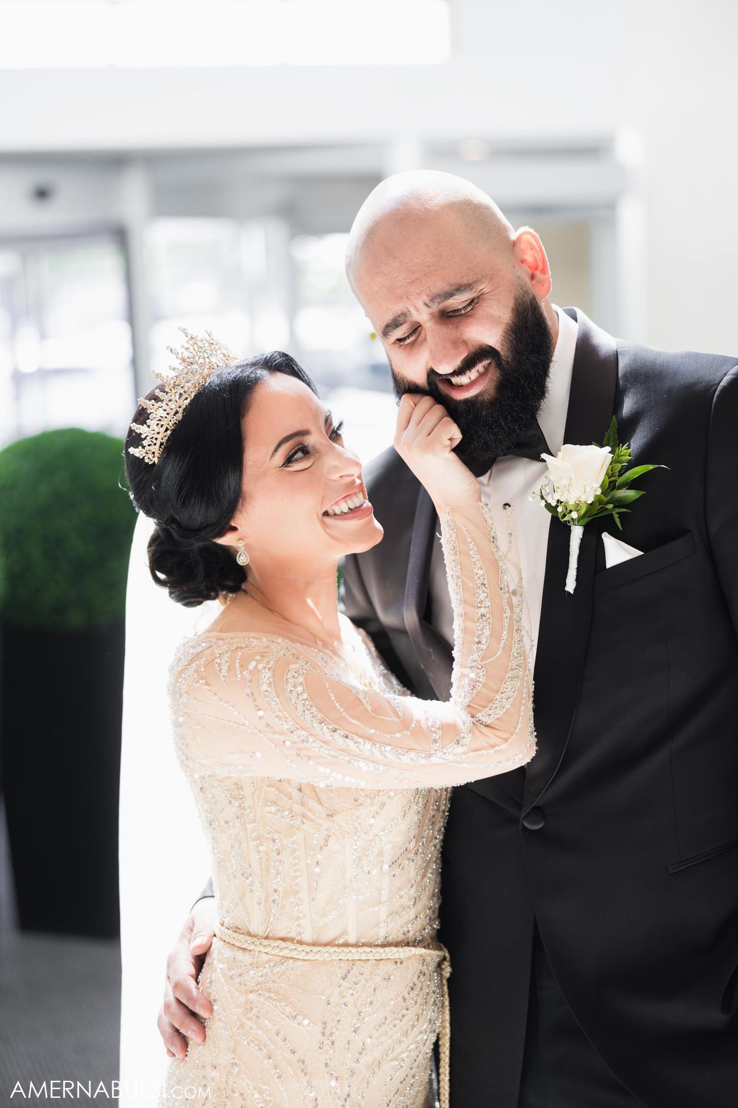 Newly married couple sharing an intimate moment in their wedding attire with a beautiful lace dress and black tuxedo.