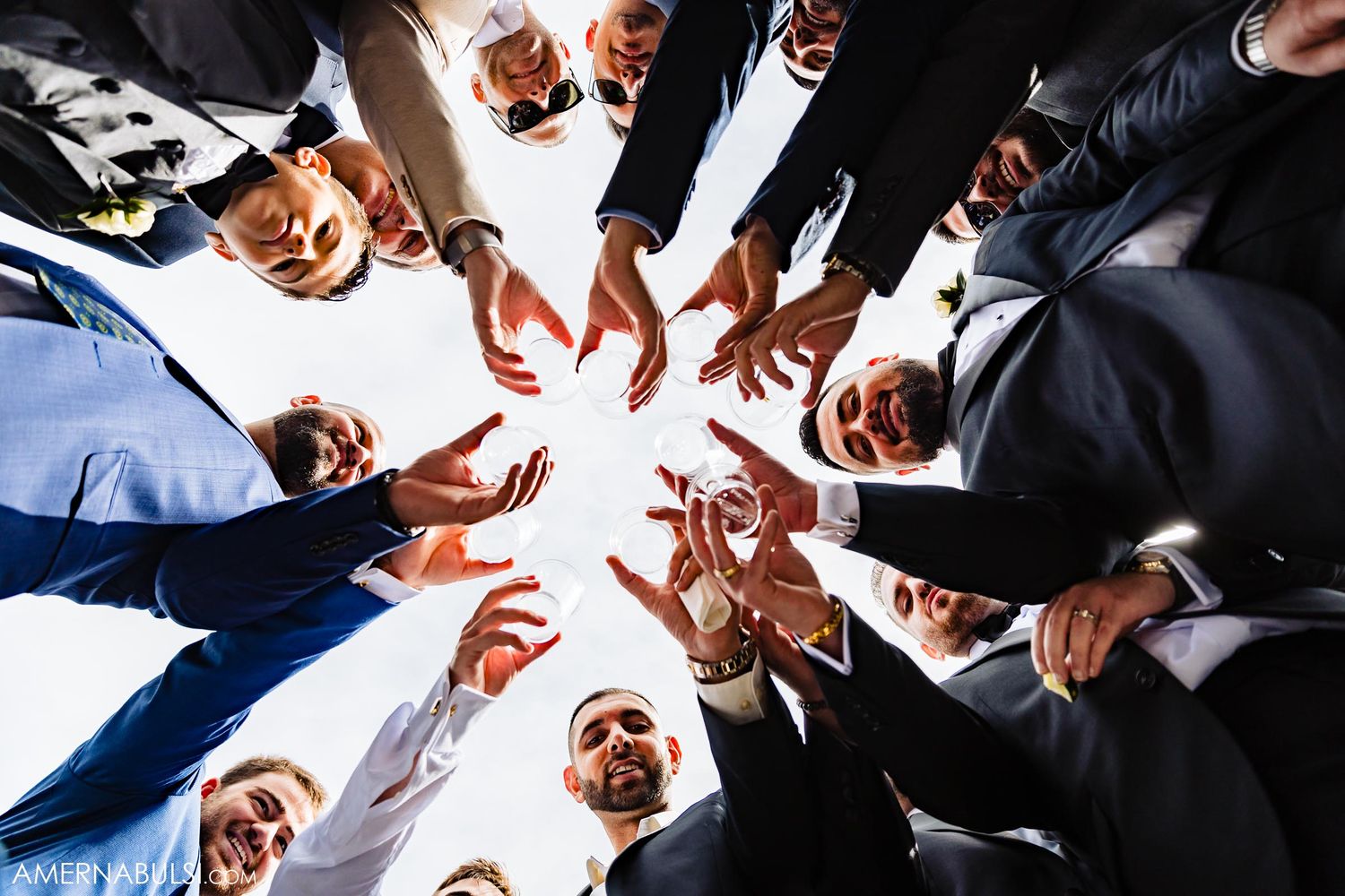 Creative overhead shot of wedding party forming circle with hands pointing inward.