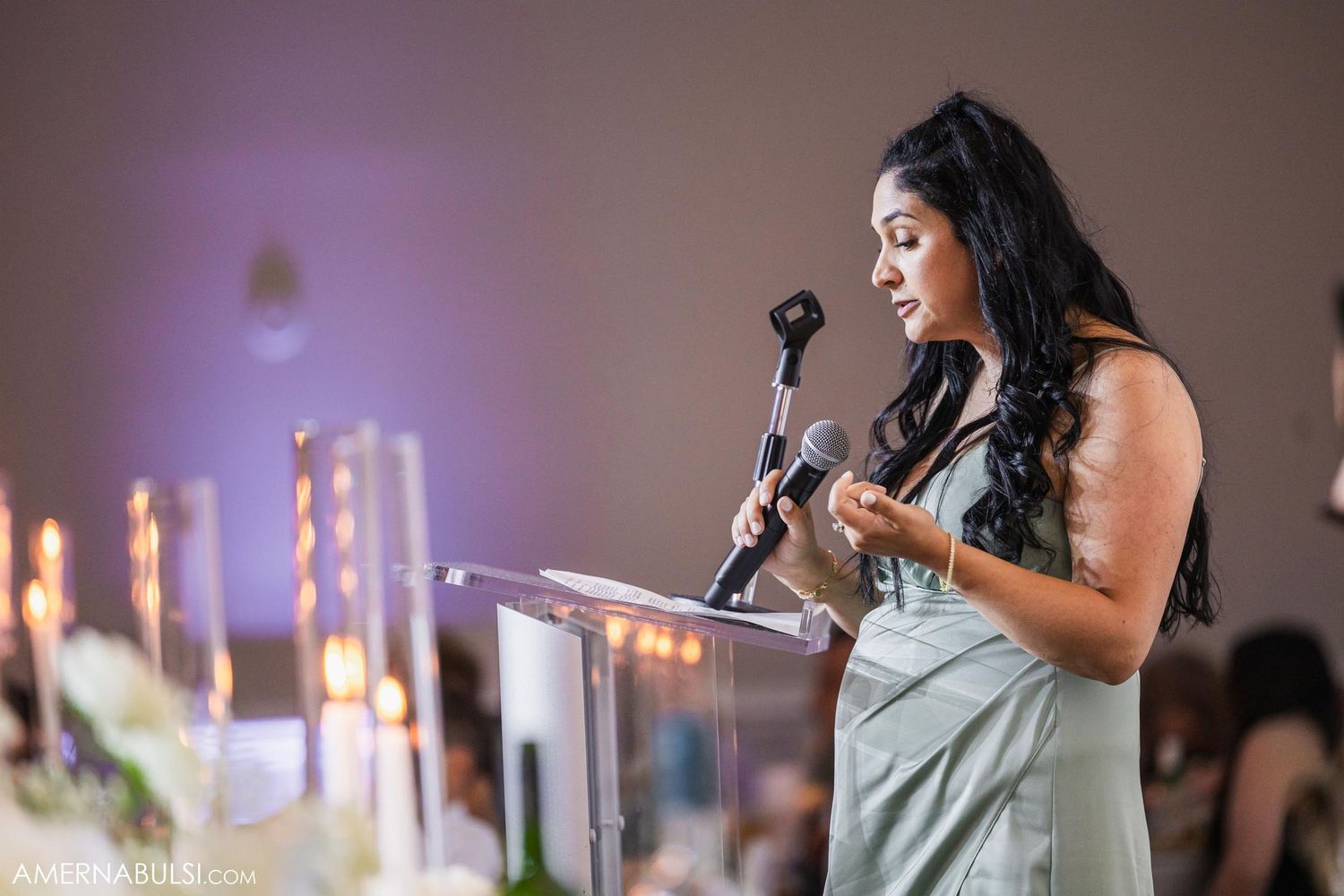 Speaker delivering emotional speech at formal event with candlelit decor.
