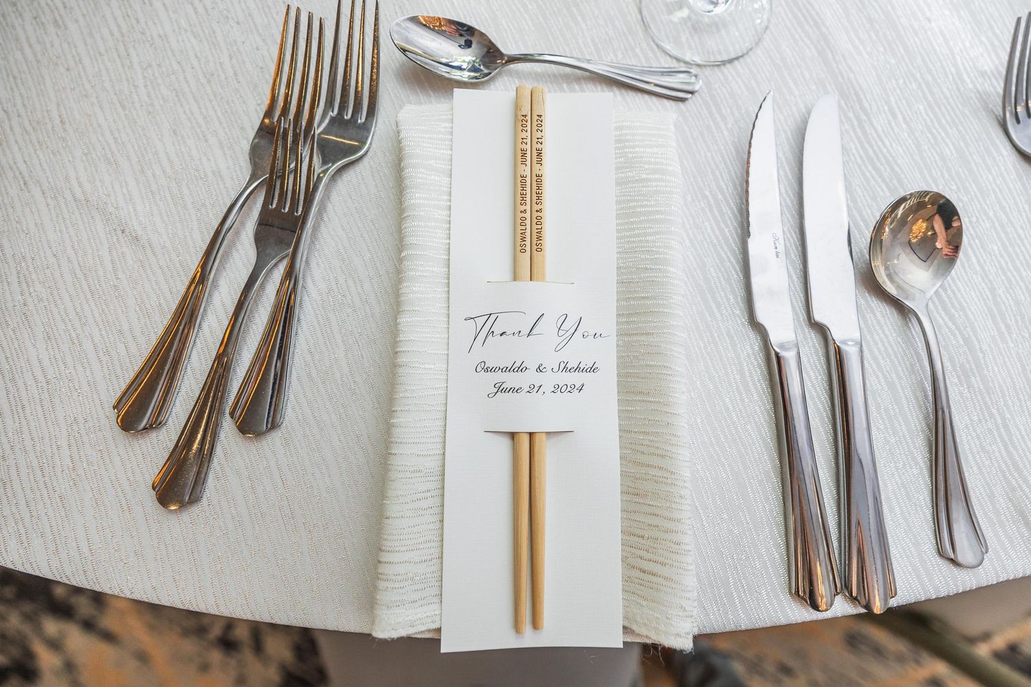 Elegant place setting with white napkin, chopsticks and thank you note on formal dining table.