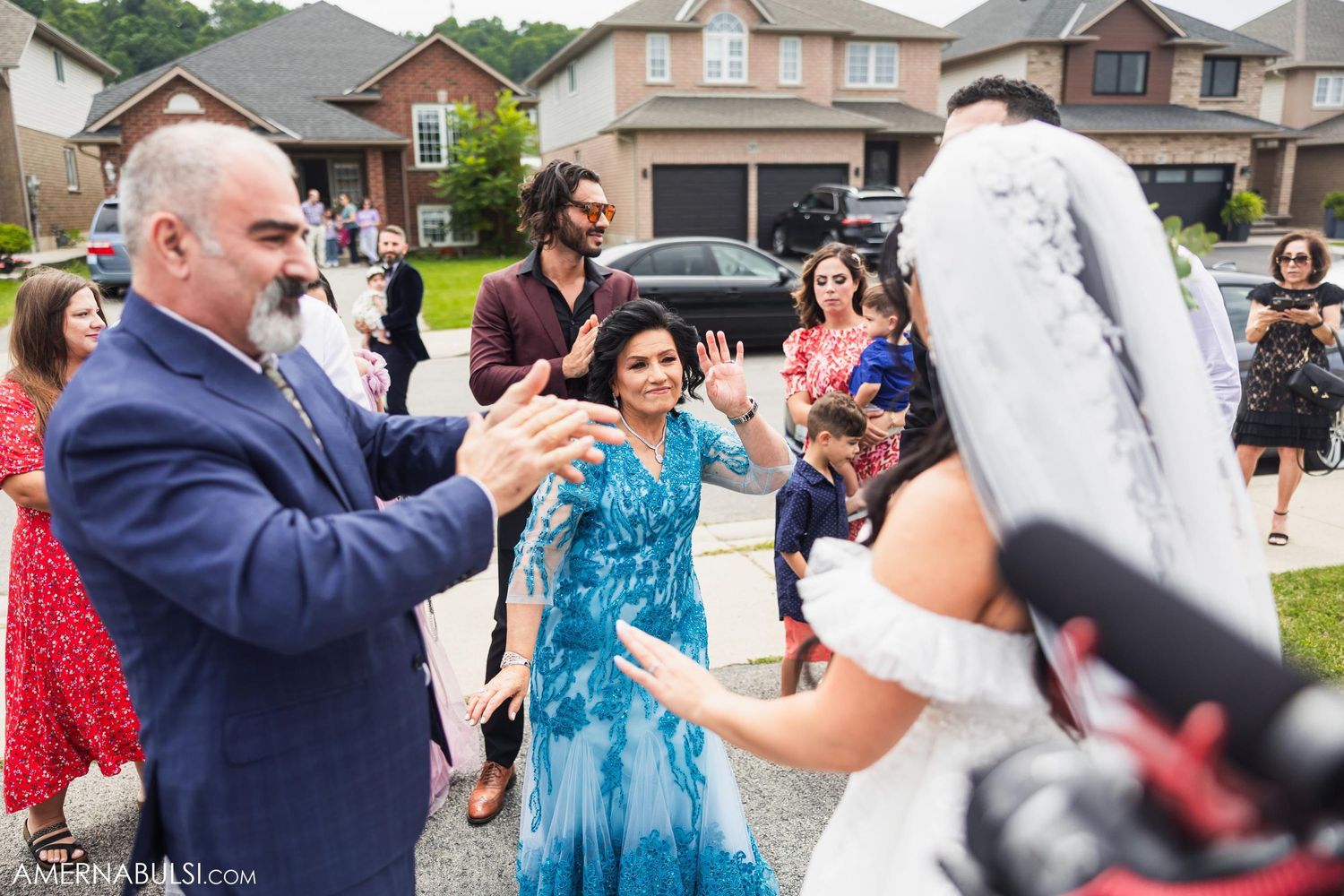 Wedding guests applaud during outdoor celebration in residential neighborhood.