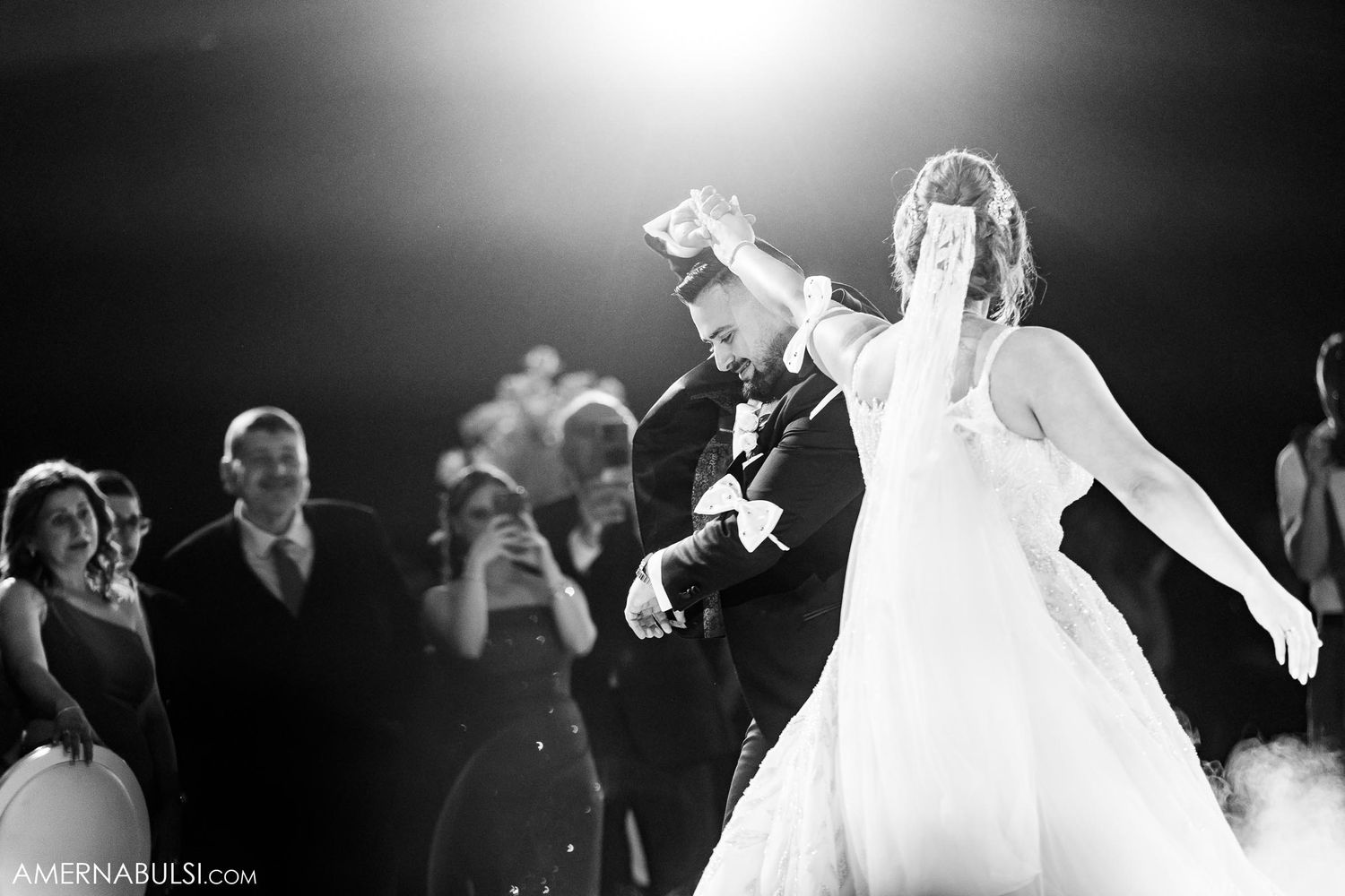 Black and white photo of newlyweds dancing with joyful expressions.