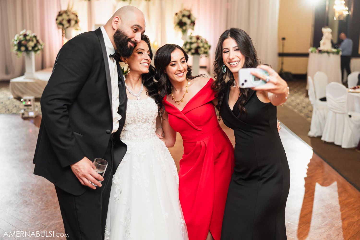 Wedding reception guests pose together for a celebratory group photo in formal attire.