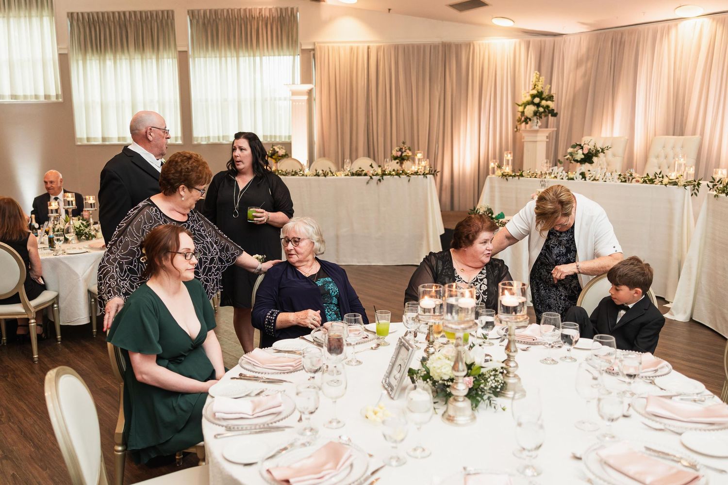 Wedding reception guests enjoying conversation at an elegantly set round dining table.