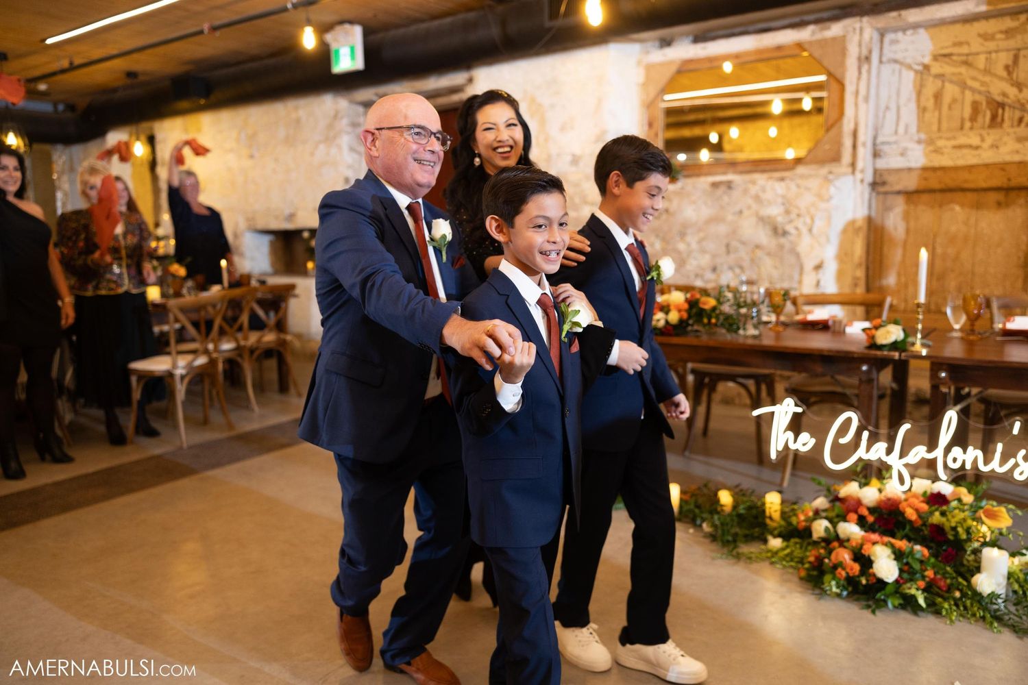 Wedding reception scene with guests dancing and celebrating in a rustic venue.