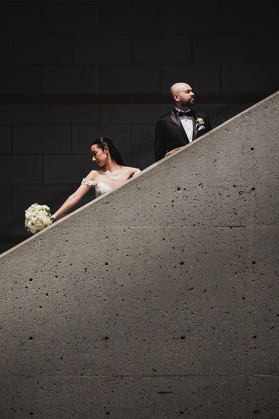 Minimalist wedding photography series on concrete featuring dramatic angles and shadows.