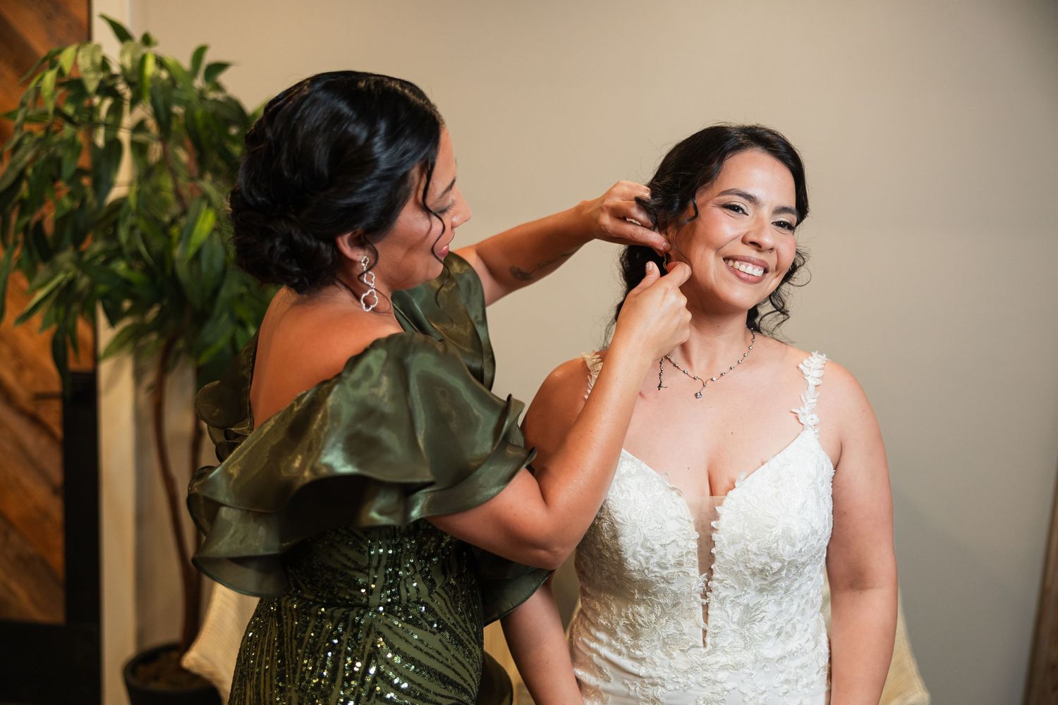 Mother helping bride put on earrings before wedding ceremony in elegant getting-ready moment.
