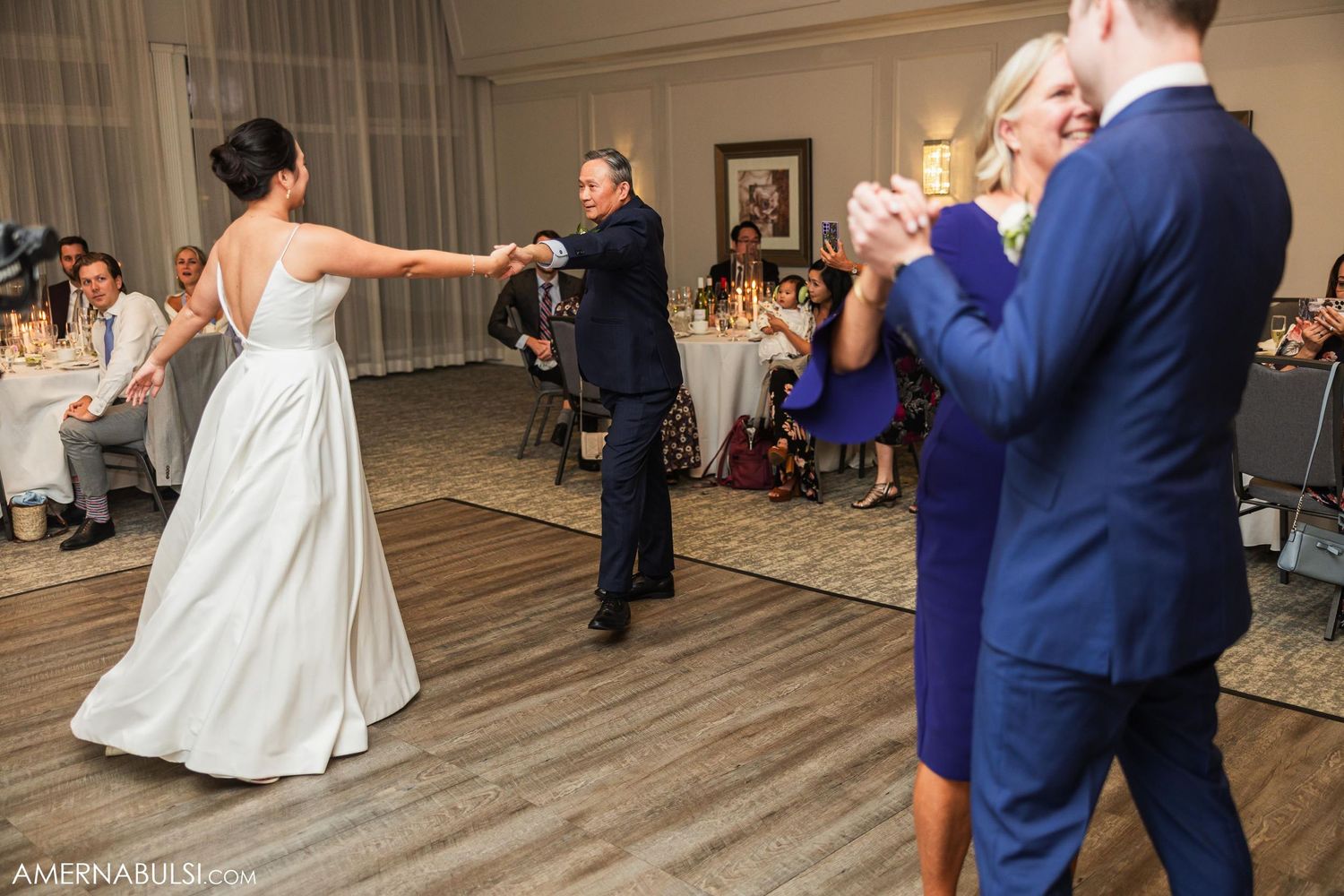 Wedding reception dancers moving across wooden dance floor in formal attire.