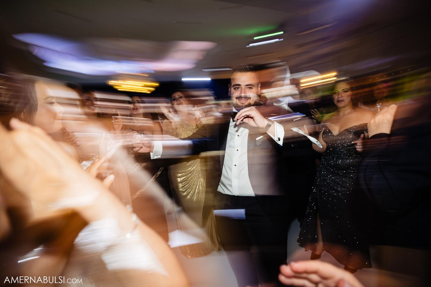 Motion-blur photograph captures energetic dancing and celebration at a wedding reception.