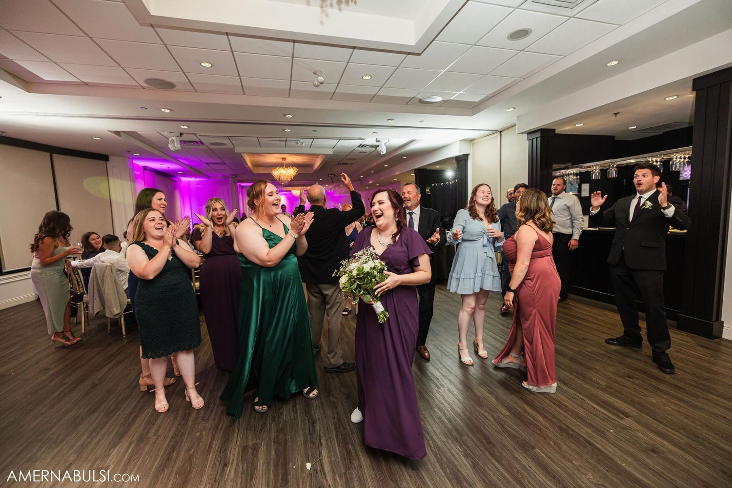 Wedding guests gathered on dance floor during reception celebration.