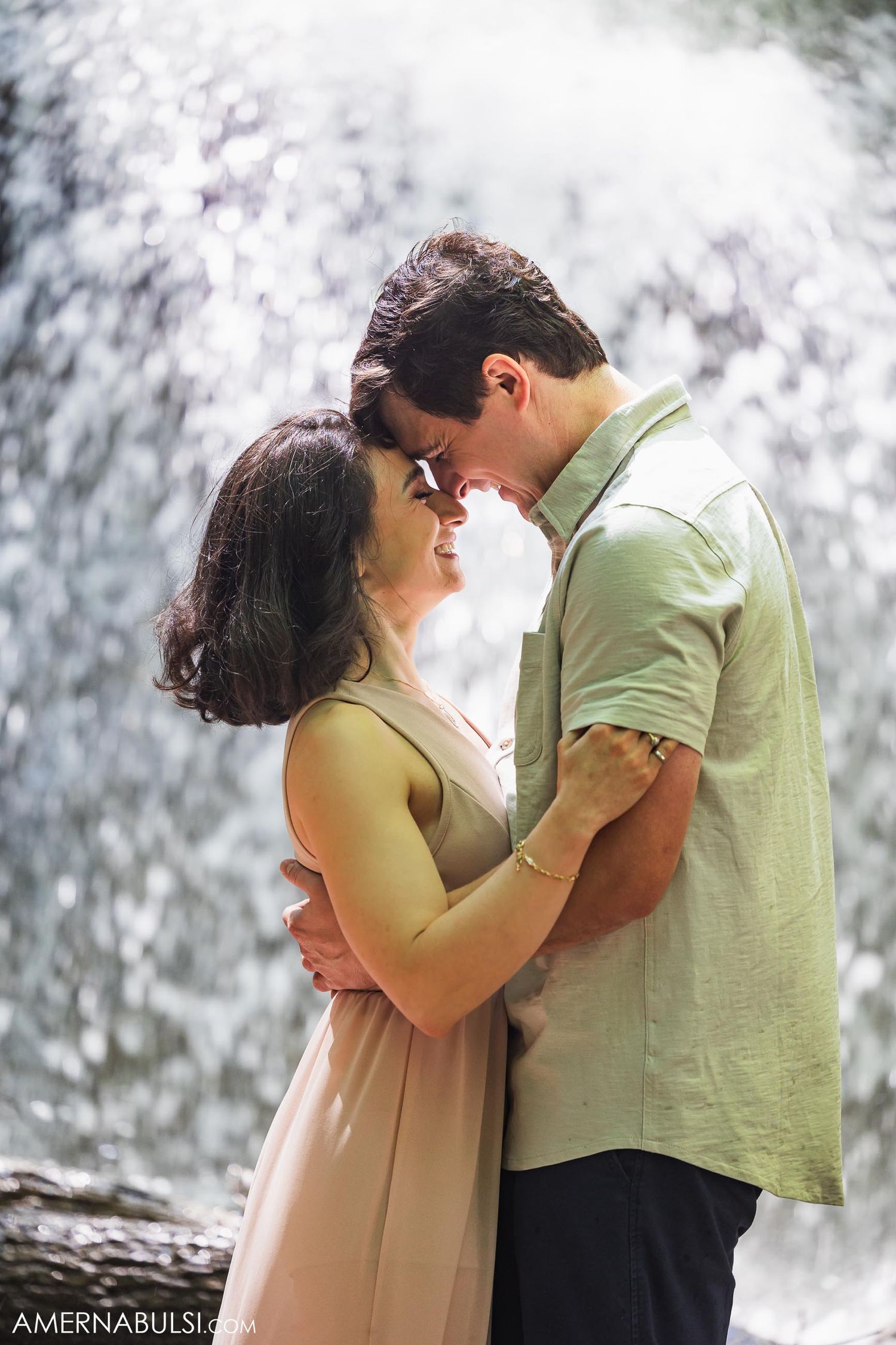 Tender moment captured between two people with misty waterfall in the background.