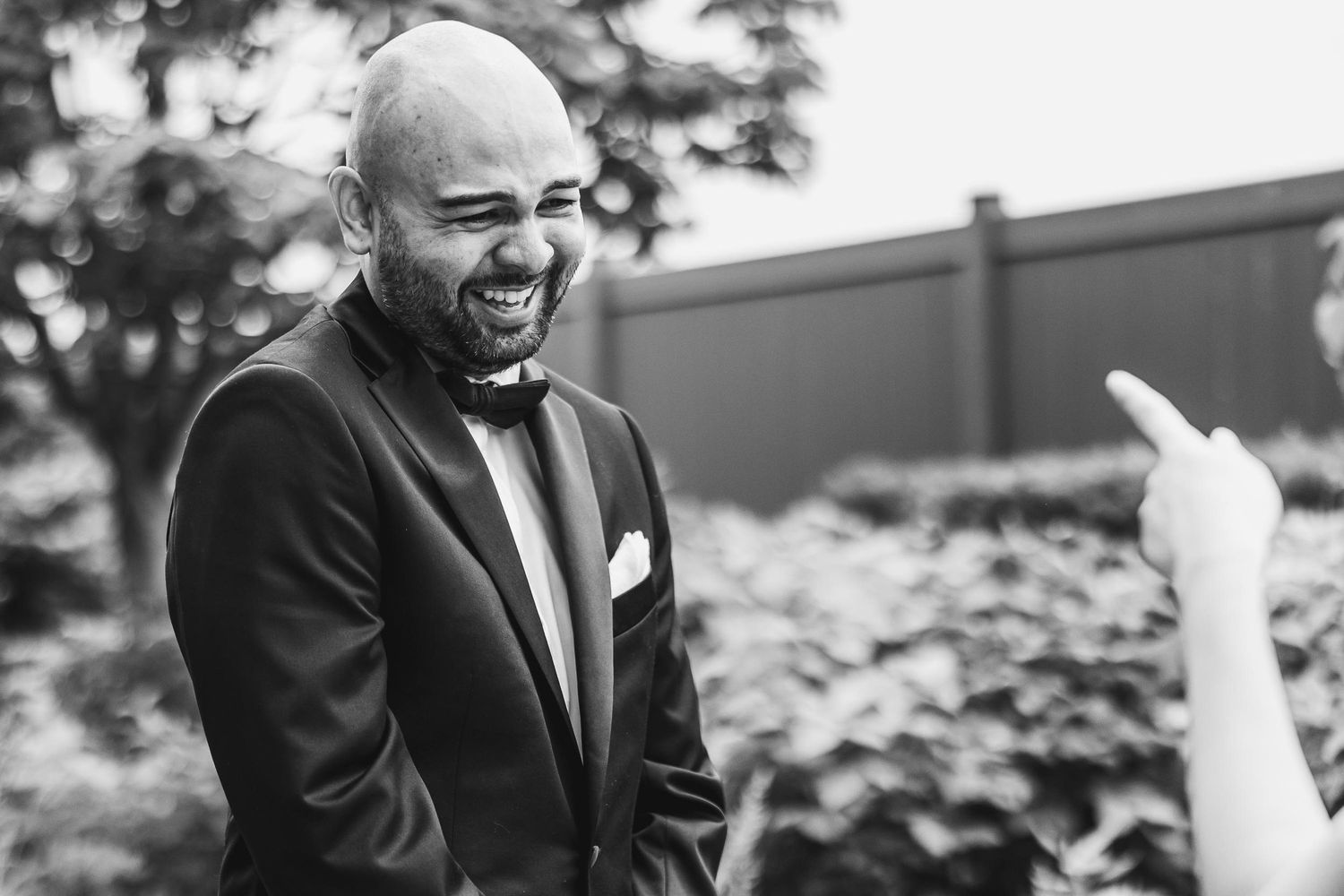 A candid black and white photo capturing joyful laughter during a wedding moment.