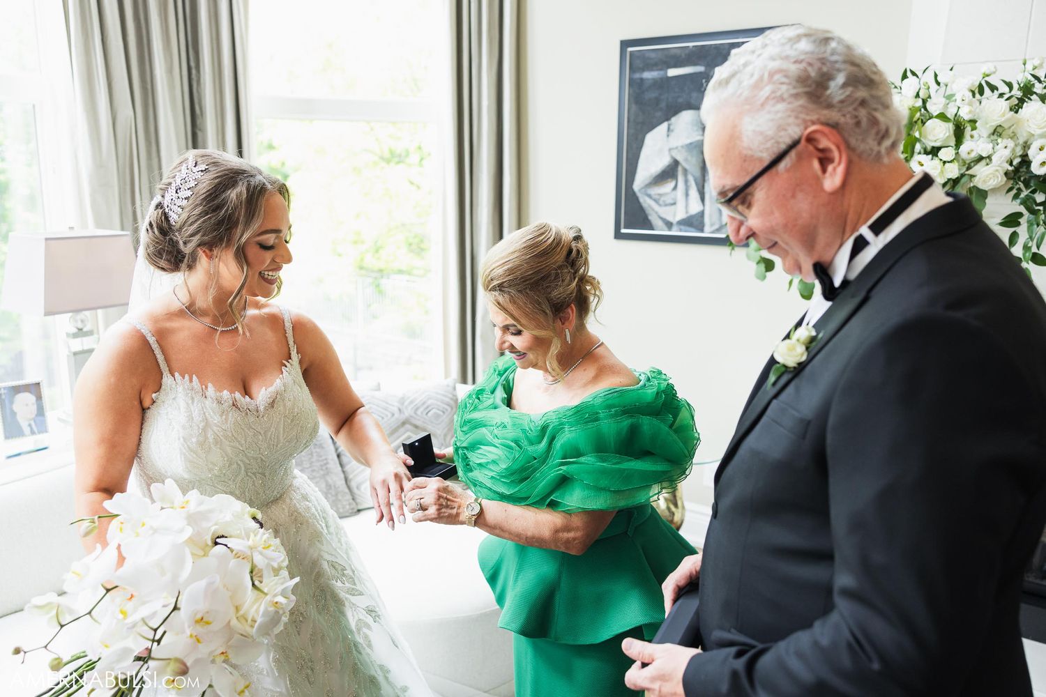 A tender moment during wedding preparations as the bride gets ready in a beautiful white gown with family assistance.
