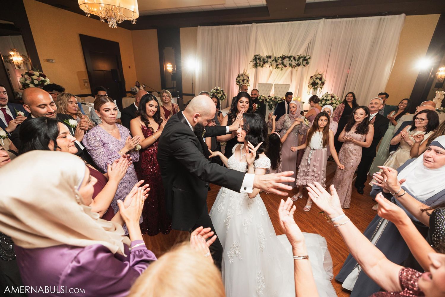 Guests cheer and reach out as the newlyweds share a romantic moment on the dance floor.