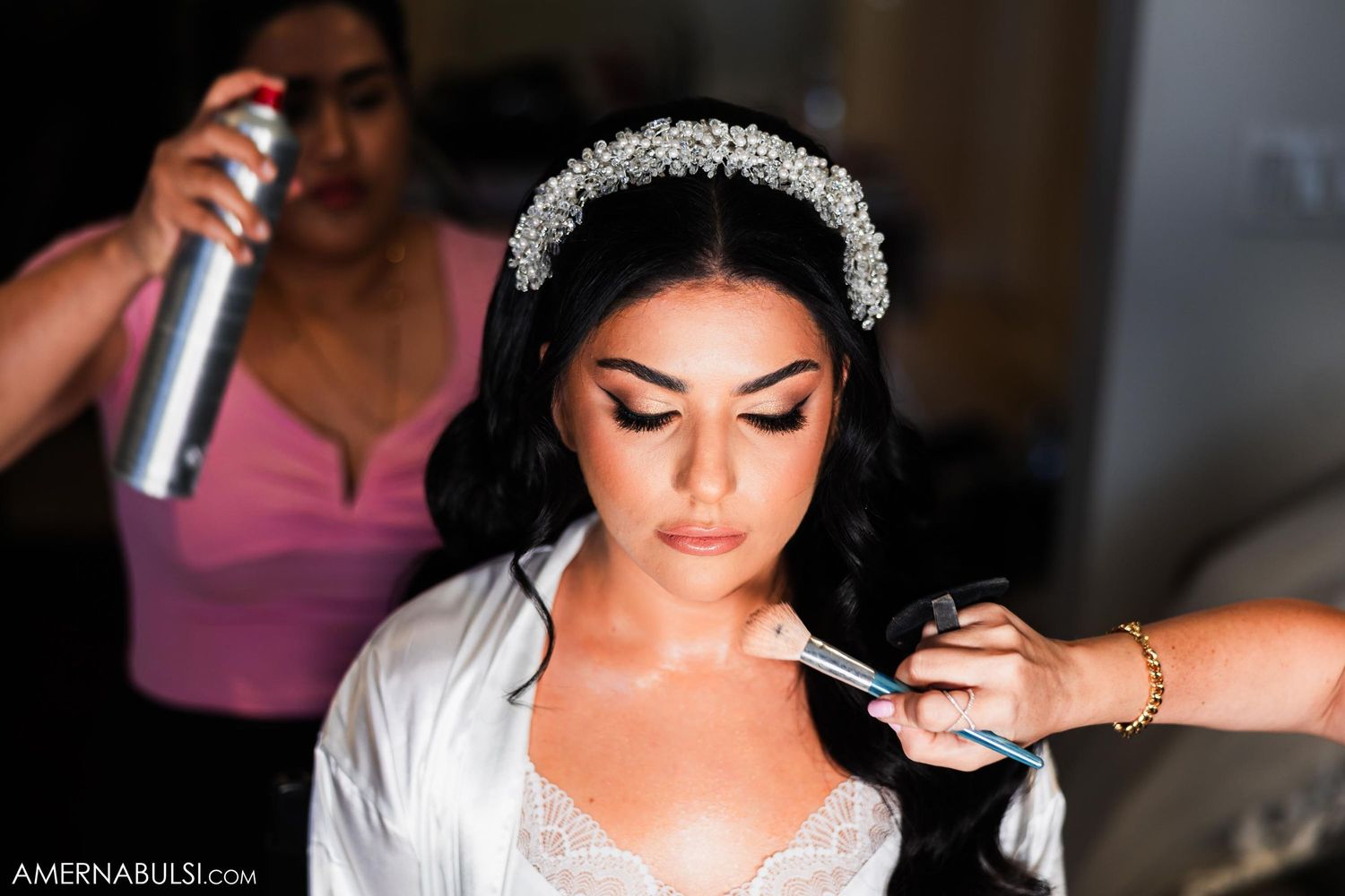 Wedding preparation scene with makeup application while wearing a crystal headpiece.