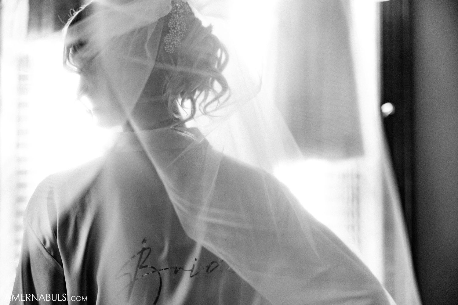 Silhouette of someone in a robe through sheer white fabric with soft lighting.